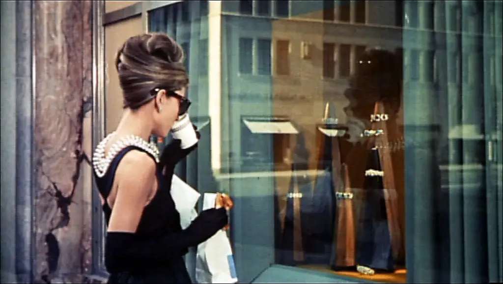 Audrey Hepburn llevando gafas oversize icónicas en *Desayuno con Diamantes*.