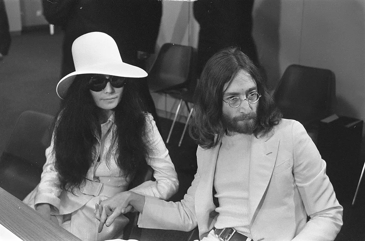 John Lennon y Yoko Ono, posando juntos en 1969, con Lennon llevando sus emblemáticas gafas redondas.
