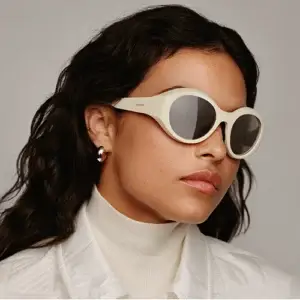 Femme portant des lunettes Moncler Futuro 0ME8005 avec une monture blanche au design sportif et élégant