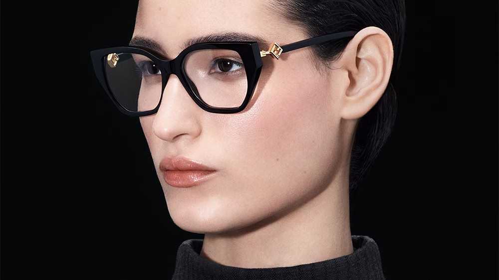 Thélios and FENDI. FENDI FF Diamonds eyeglasses feature a black acetate cat-eye frame adorned with a gold logo on the temples. Timeless elegance and bold style, perfect for a sophisticated and modern look.