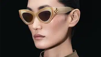 Una mujer elegante luce las gafas de sol FENDI FF Diamonds en tono dorado, con una montura gruesa de estilo ojo de gato y un logotipo incrustado, destacando un estilo sofisticado y moderno.
