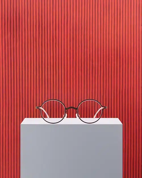 Lunettes MYKITA | Park Seo-Bo en rouge Maple Leaf, exposées devant une œuvre de l’artiste coréen.