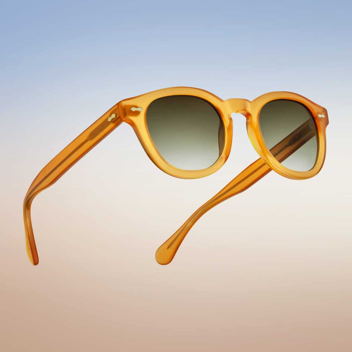 Gafas de sol Dorata, vista tres cuartos trasera, montura en acetato amarillo miel transparente, remaches en rombo, patillas finas, lentes verdes degradadas