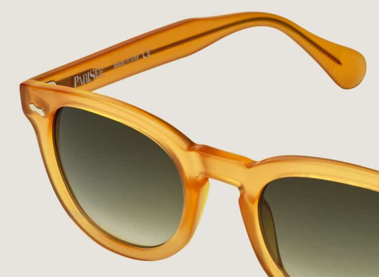 Détail lunettes de soleil Dorata, gros plan sur la monture en acétate jaune miel transparent, rivet en losange, verres dégradés vert, marquage PARISEE Made in Italy sur la branche