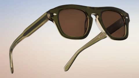 Vista trasera en tres cuartos de las gafas de sol Freschezza en acetato verde oliva translúcido con lentes marrones, sobre fondo de cielo degradado