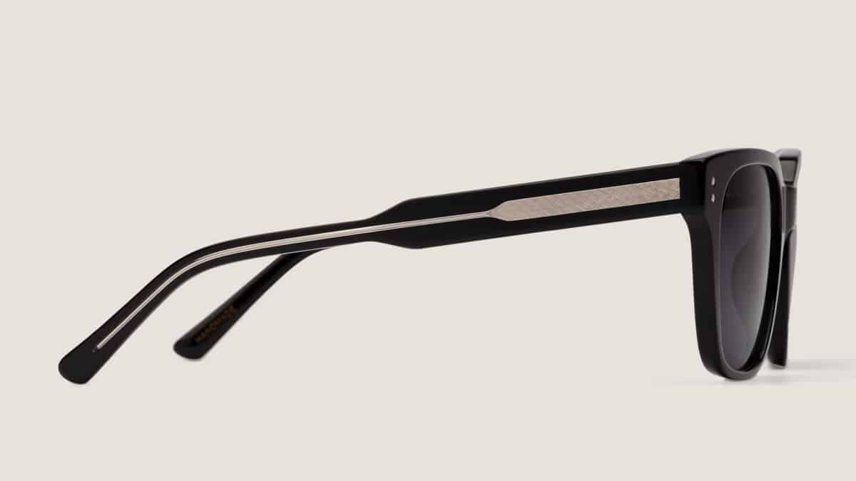 Detalle lateral de la varilla de las gafas de sol Essentiel N1 en acetato negro mate con inserto metálico texturizado y lentes gris oscuro