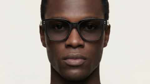 Retrato de estudio de un hombre con gafas de sol negras PARISEE, forma rectangular suavizada, lentes oscuras.