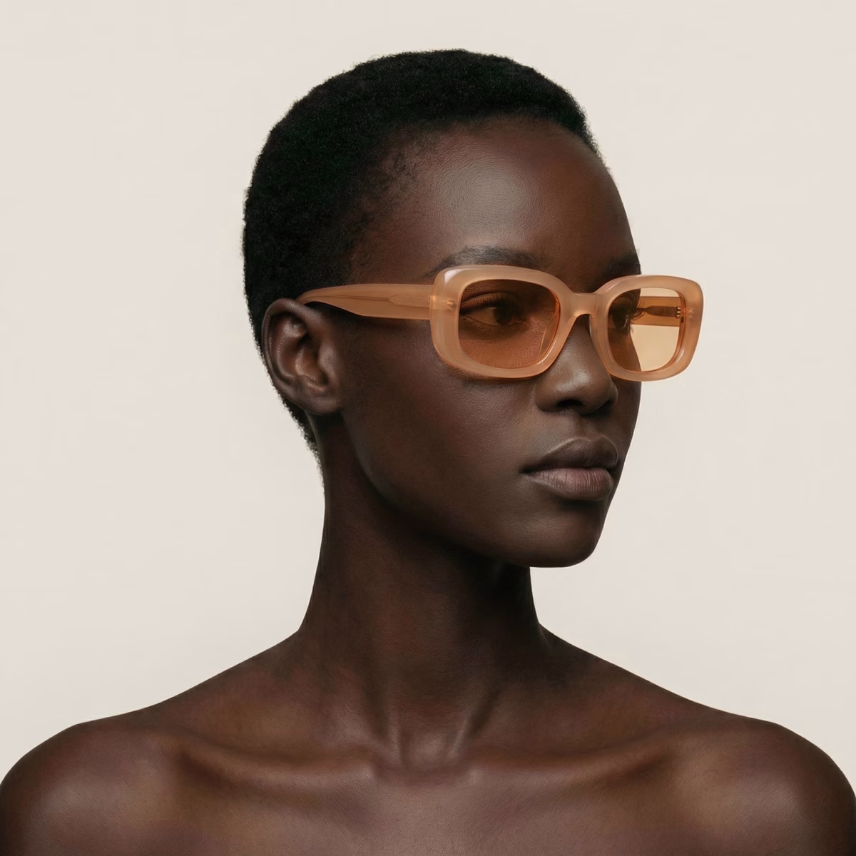 Studio portrait of a model wearing Parisee Eyewear Essentiel N3 beige translucent sunglasses, softened rectangular frame, light tinted lenses
